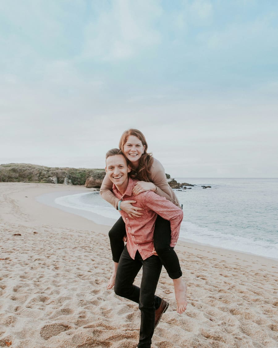A woman smiling with her companion in bright coastal light.