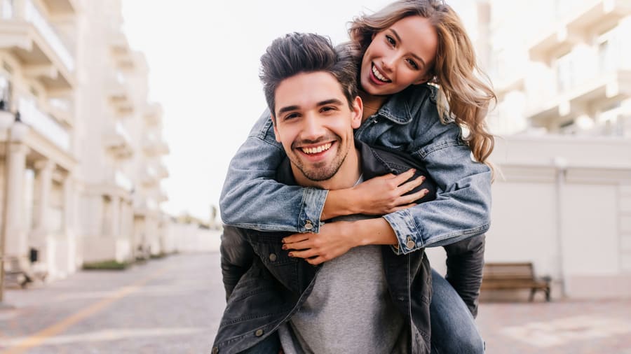 A woman laughing beside a warm male companion in an easy social moment.