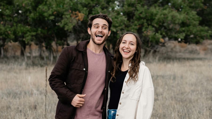 A woman laughing beside a warm male companion in an easy social moment.
